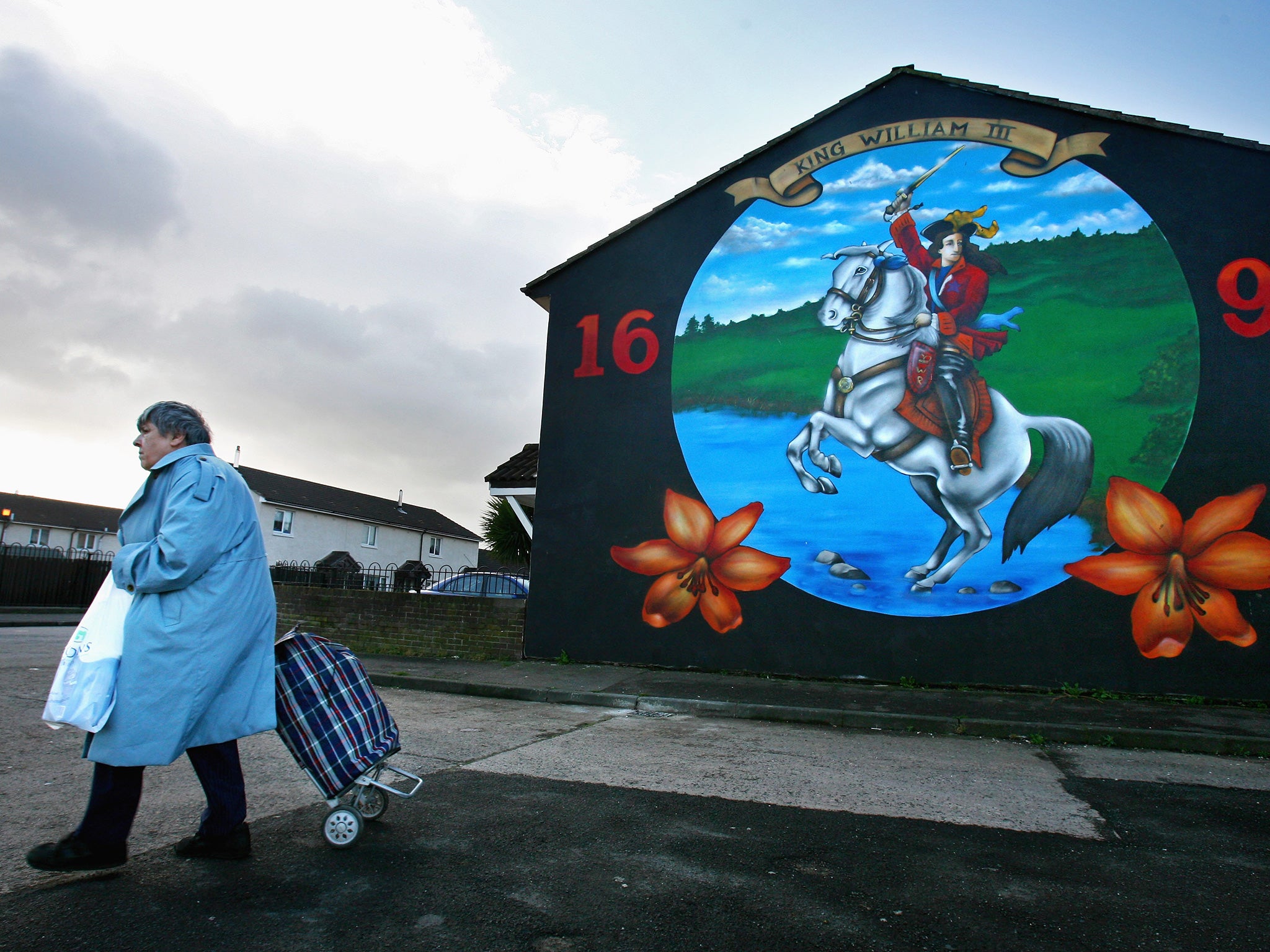 A woman walks past a protestant loyalist mural in the Shankhill area