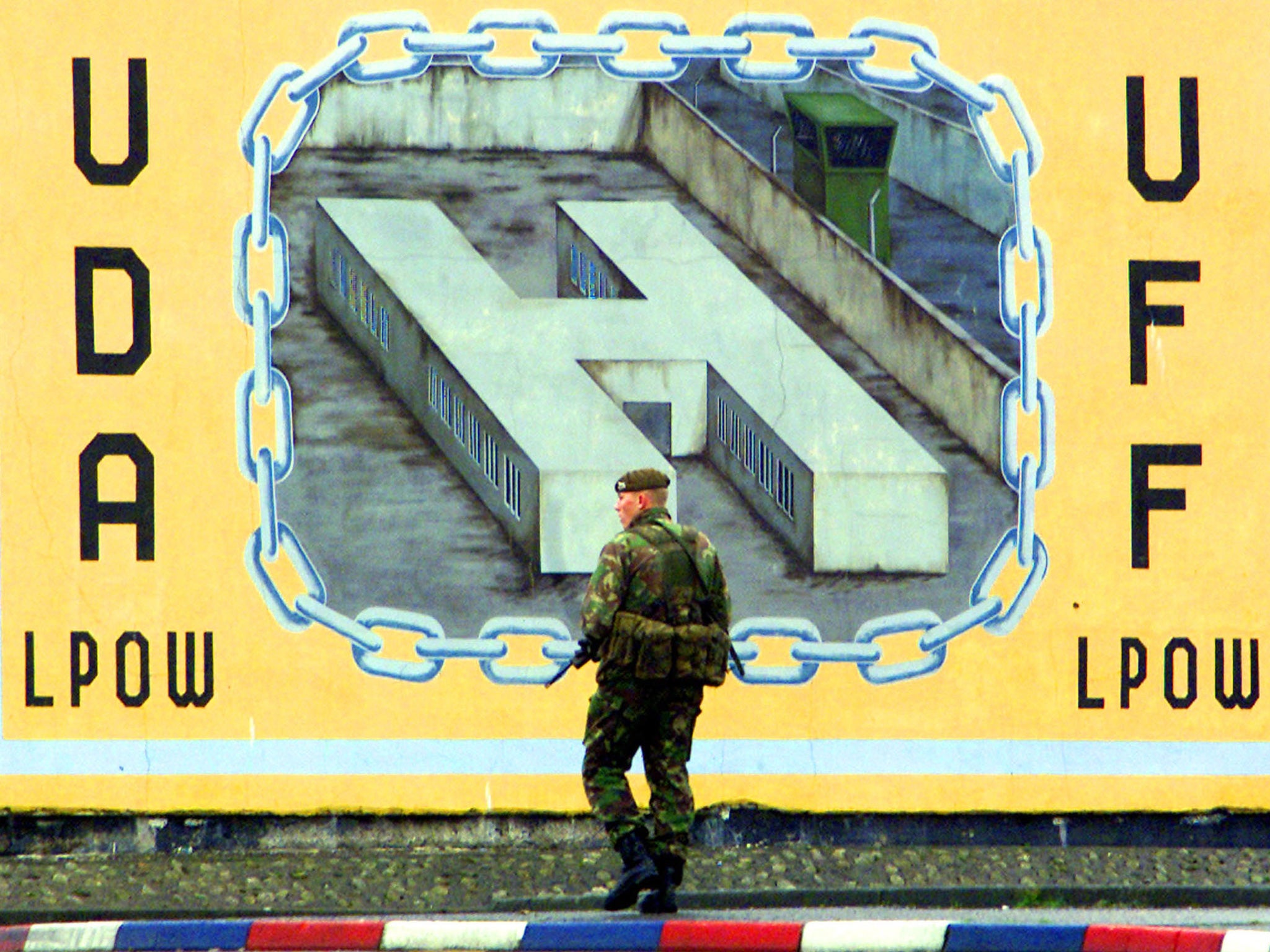 A British soldier patrols the Lower Shankill district in front of a mural from the Ulster Defence Association (UDA)