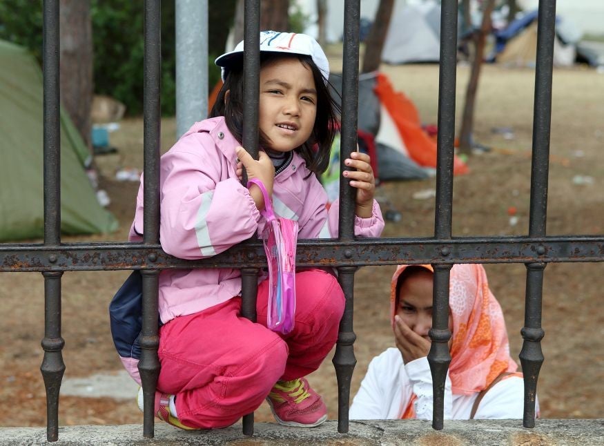 Refugees look through the fence around the asylum processing centre in Traiskirchen