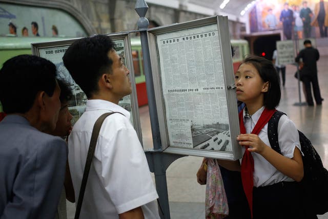 North Koreans read public copy of the daily newspaper at the platform of a subway station in Pyongyang (AP)