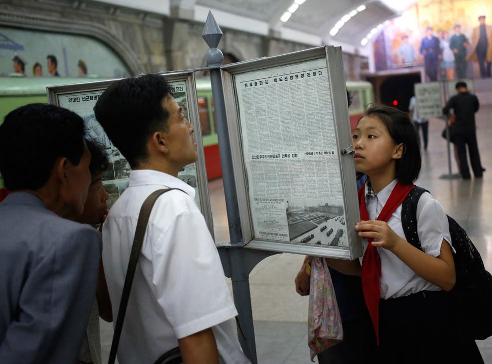 North Koreans read public copy of the daily newspaper at the platform of a subway station in Pyongyang (AP)