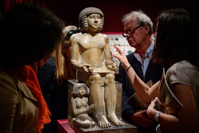 Members of the public and gallery staff examine The Northampton Sekhemka, an Egyptian painted limestone statue