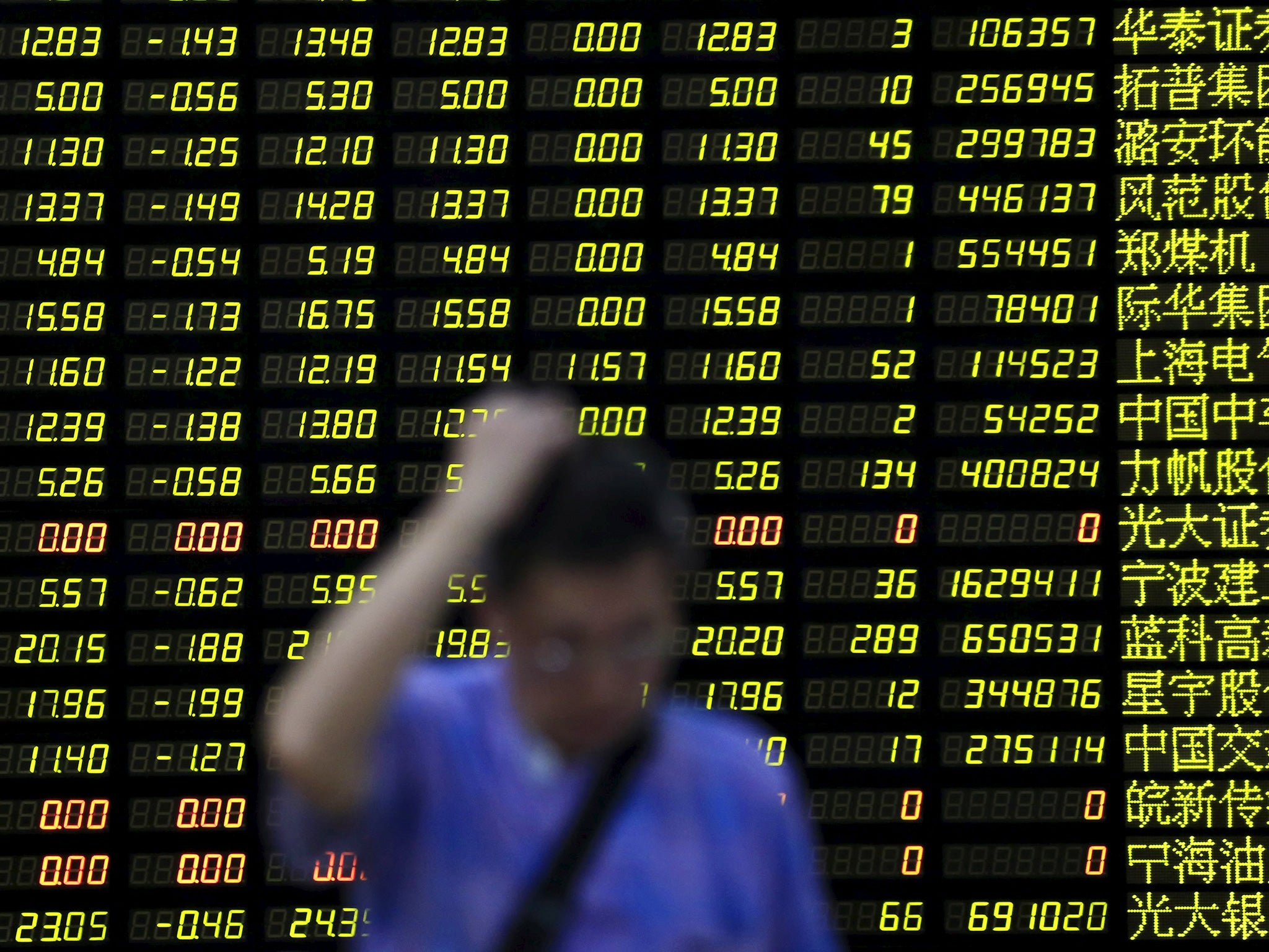 An investor stands in front of an electronic board showing stock information at a brokerage house in Shanghai, China, August 24, 2015.