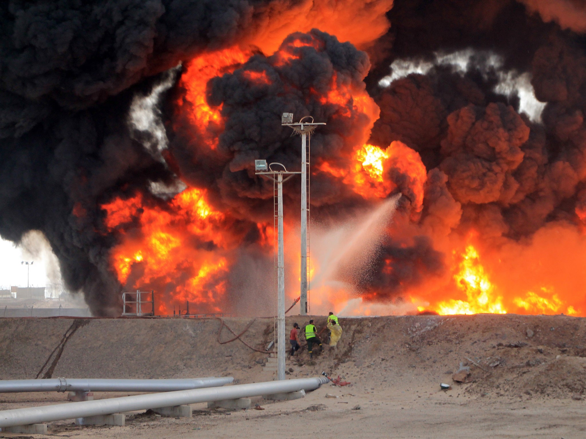 Yemeni fighters of the southern separatist movement and firefighters attempt to extinguish a flame at an oil refinery in the city of Aden