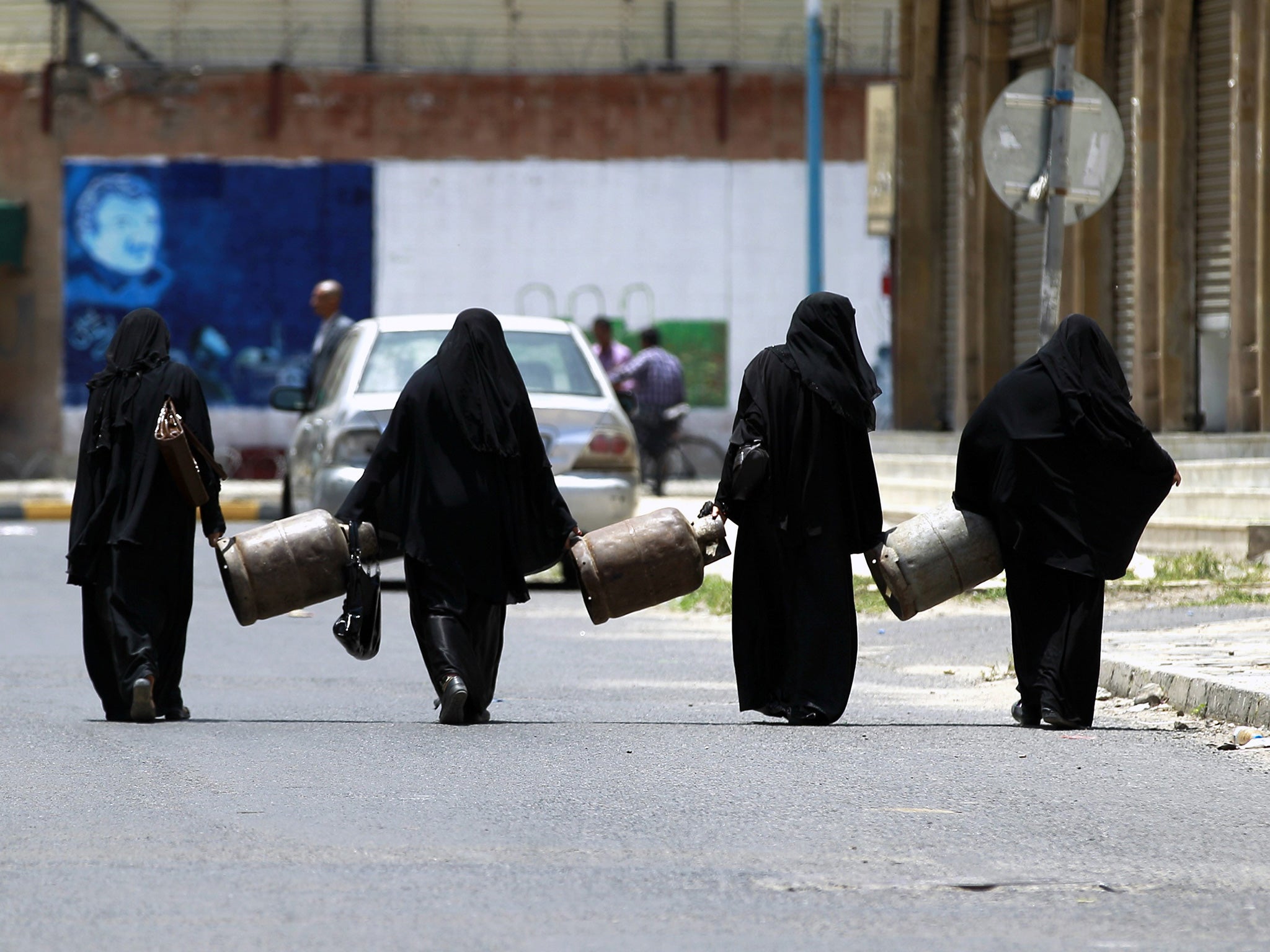 Yemeni women carry empty gas cylinders in Sanaa