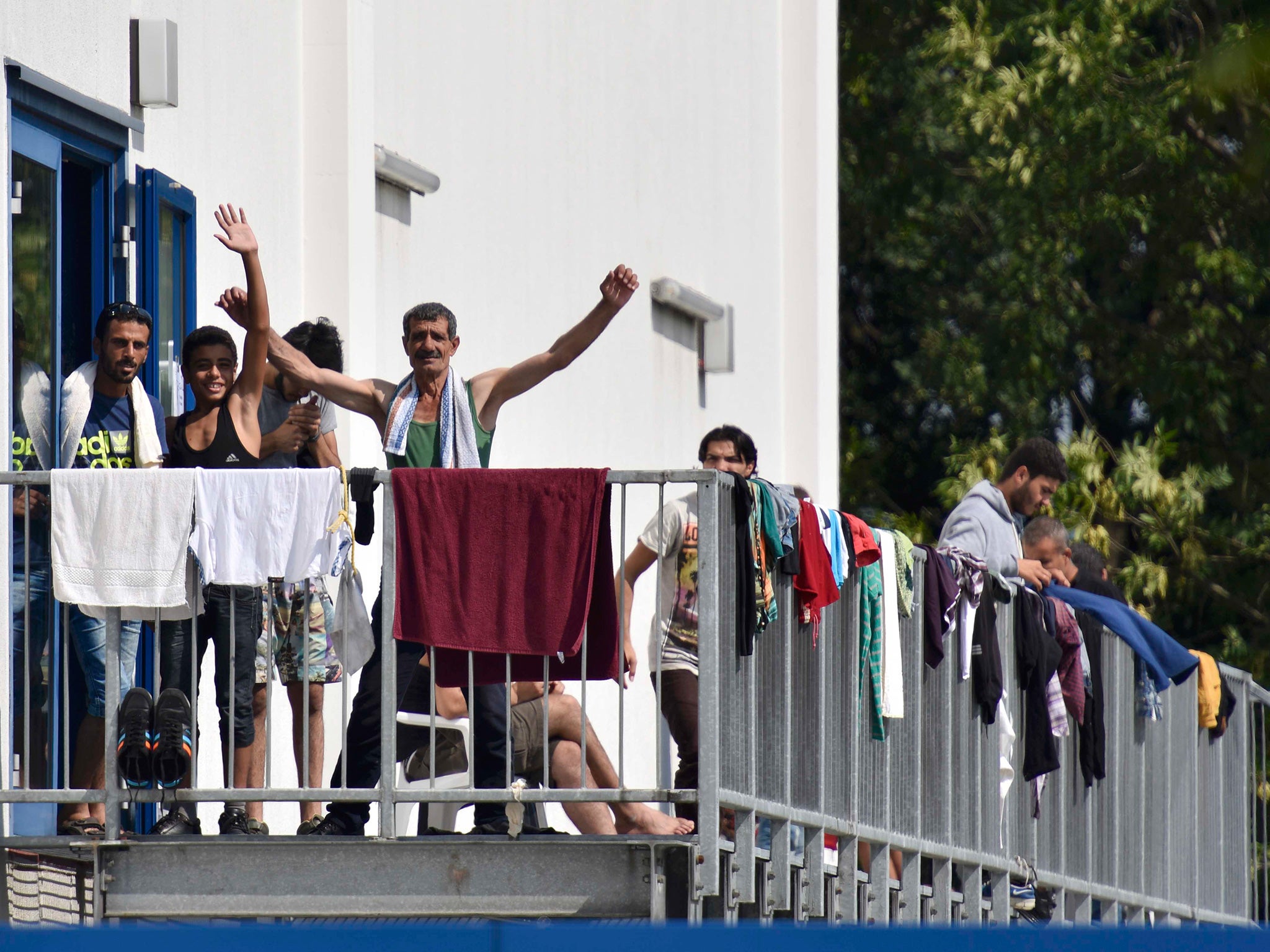 Migrants wave as they stand on the staircase of an asylum seekers accomodation facility in the eastern German town of Heidenau (Reuters)