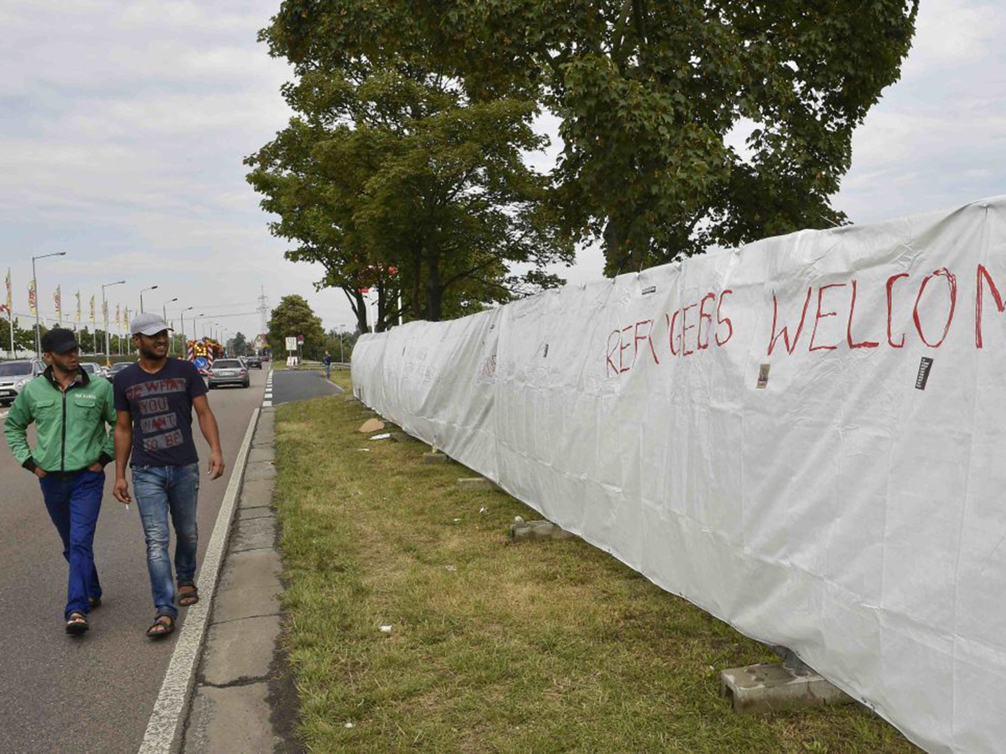 Two migrants walk along a fence of an asylum seekers accomodation facility in the eastern German town of Heidenau