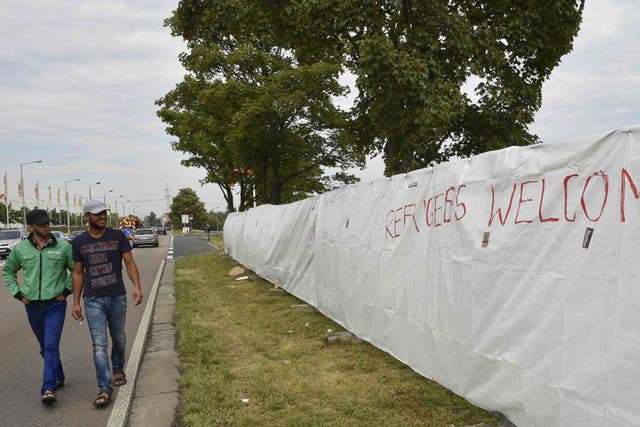 Two migrants walk along a fence of an asylum seekers accomodation facility in the eastern German town of Heidenau