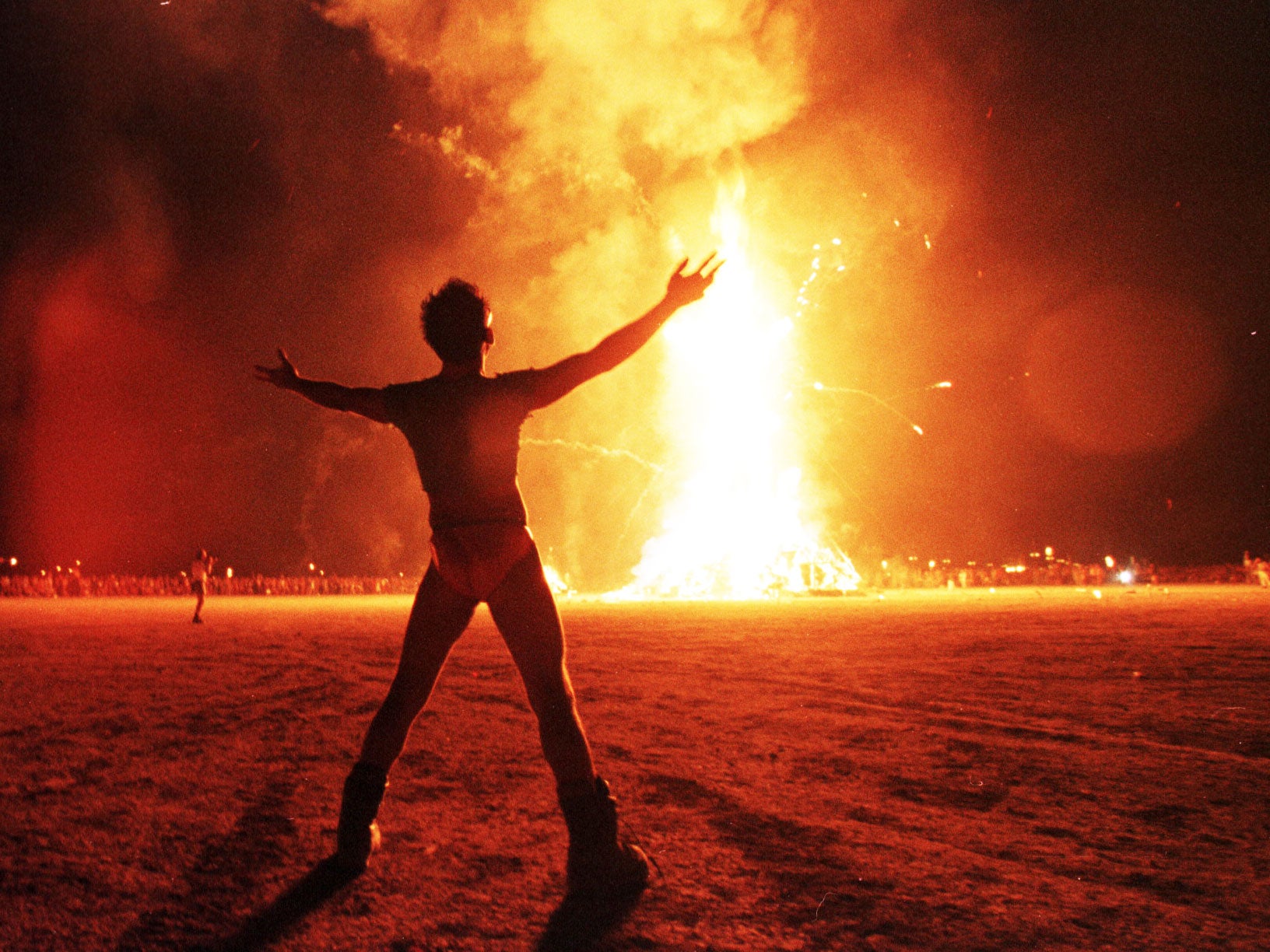 A burner watches as the Burning Man festival culminates with the burning of a giant wooden effigy
