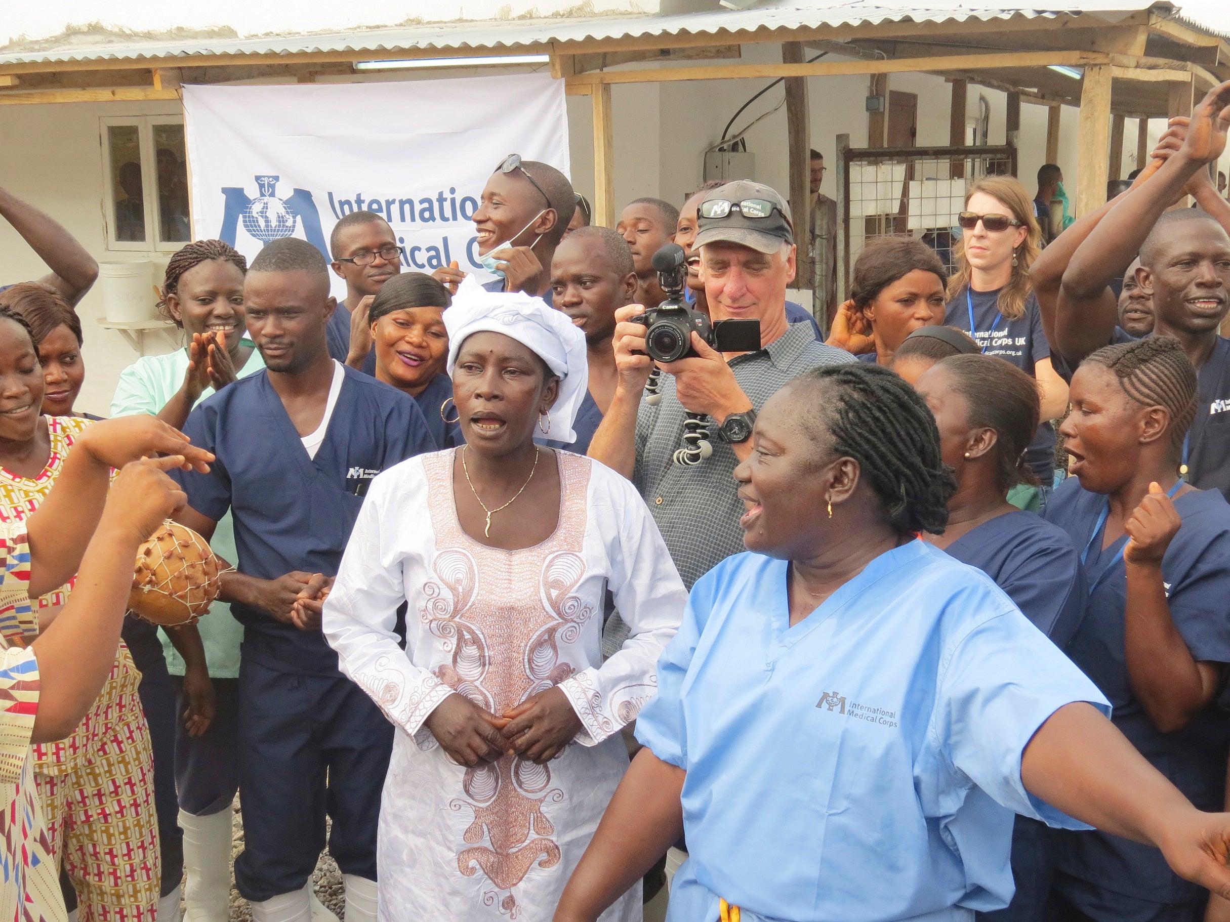Adama Sankoh who contracted Ebola after her son died from the disease late last month stands with health officials the moment after she was discharged