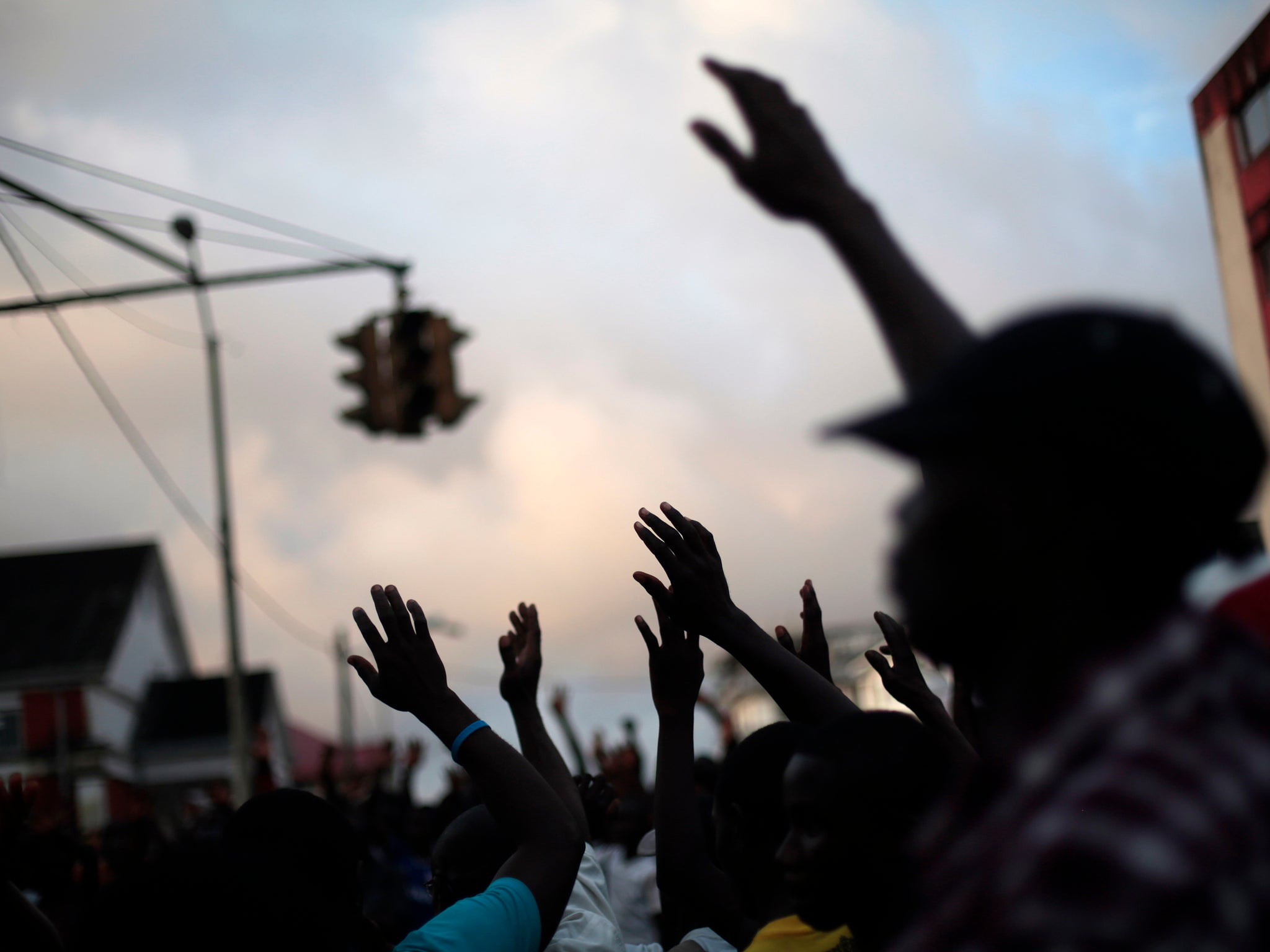 bystanders listen to a street preacher calling on people to raise their hands and "Wave Ebola Bye Bye"