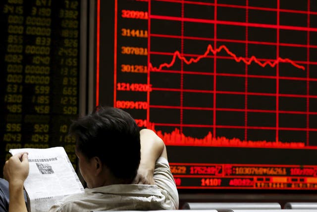 An investor reads a newspaper in front of an electronic board showing stock information at a brokerage house in Beijing, China.  China's major stock indexes sank more than 6 percent in early trade on Tuesday, after a catastrophic Monday that saw Chinese exchanges suffer their biggest losses since the global financial crisis, destabilising financial markets around the world.