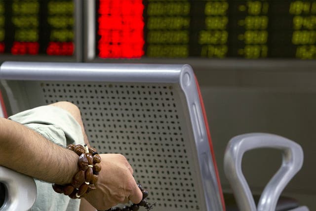 A Chinese investor holds prayer beads as he monitors stock prices at a brokerage house in Beijing