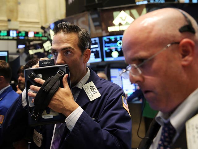 Stock traders look on in the New York Stock Exchange as markets rally, only to fall late in the day