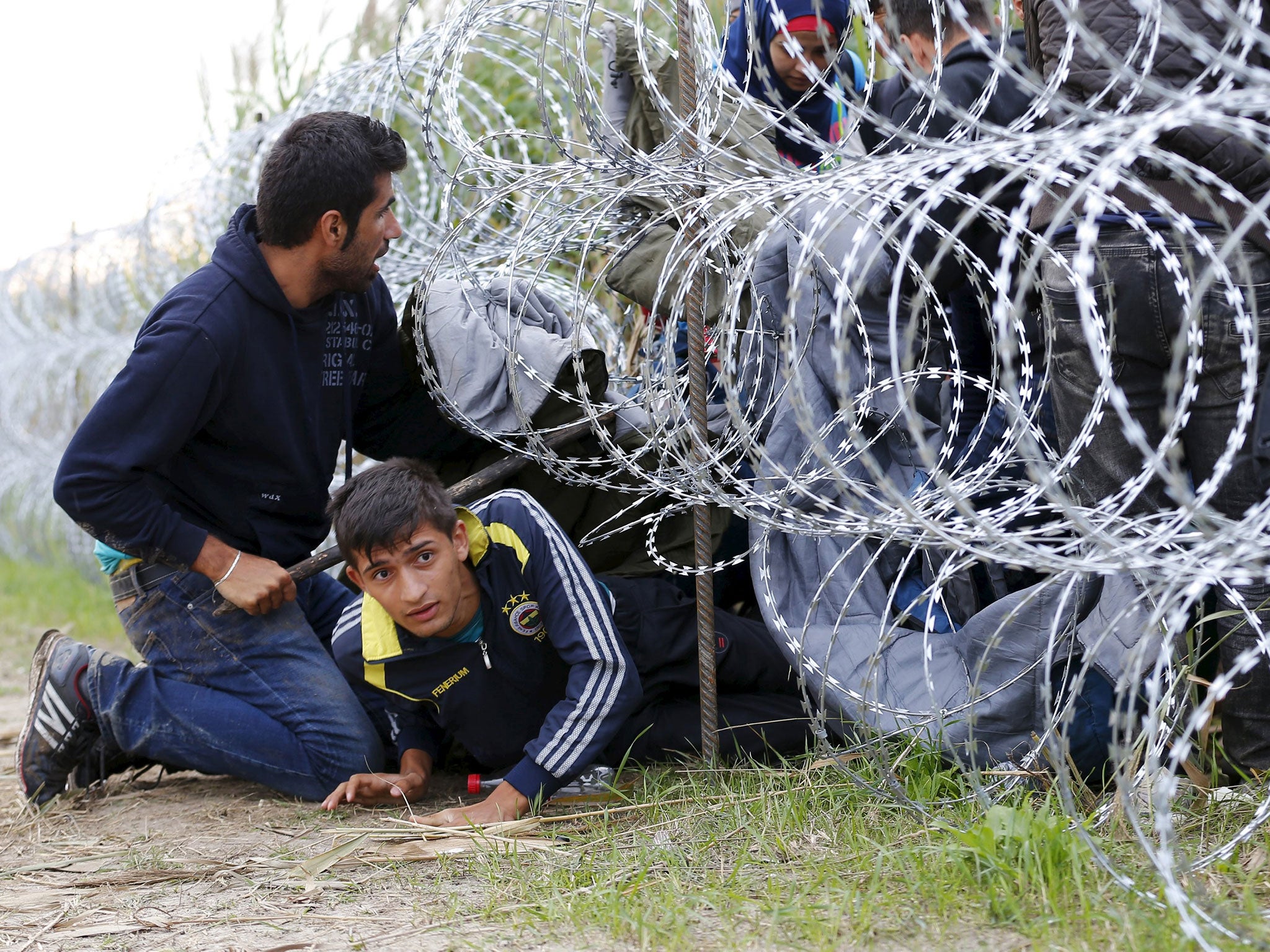 Syrian migrants cross under a fence into Hungary at the border with Serbia, near Roszke, 26 August, 2015