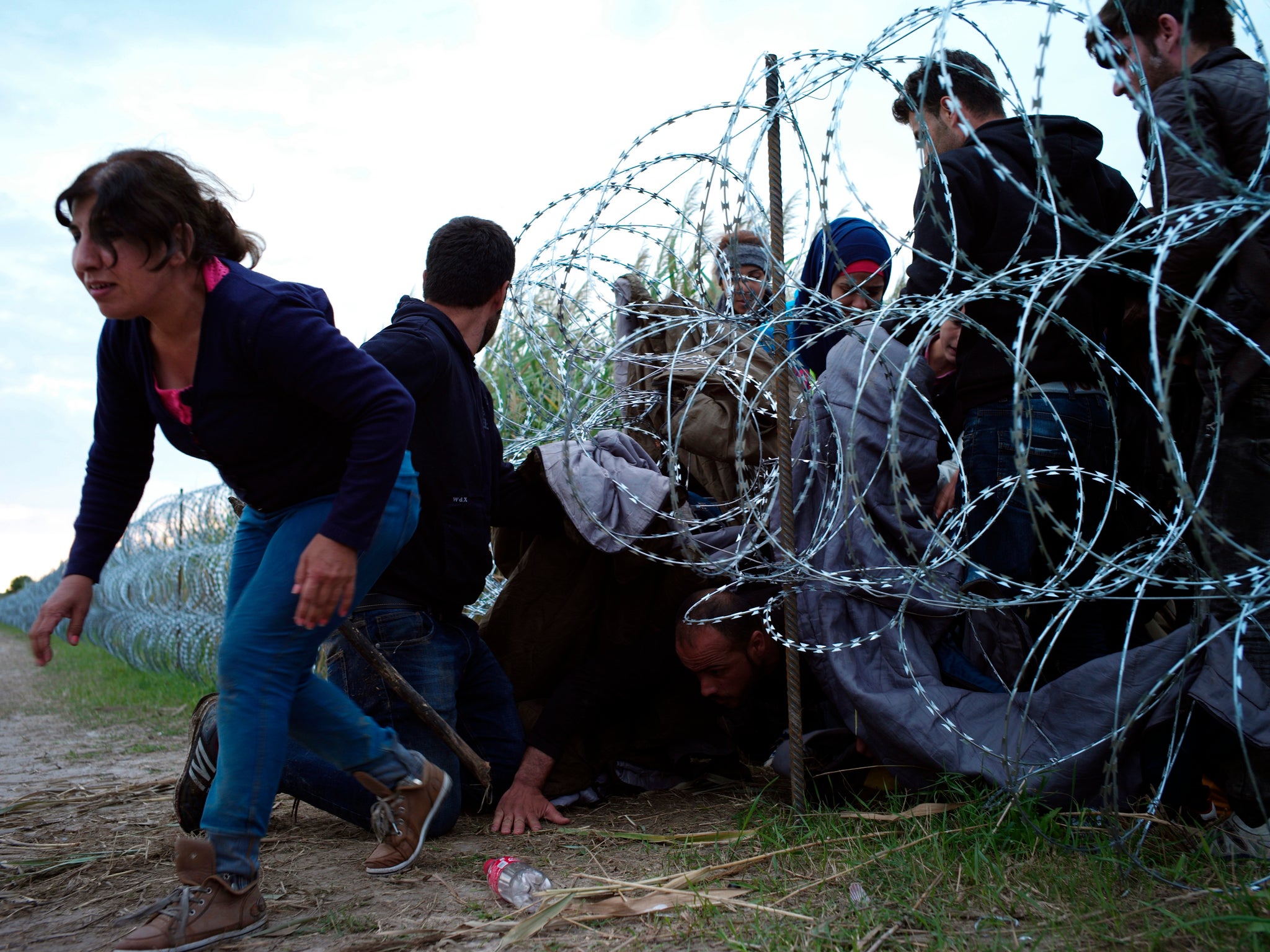 Syrian refugees cross into Hungary underneath the border fence on the Hungarian/Serbian border near Roszke, Hungary