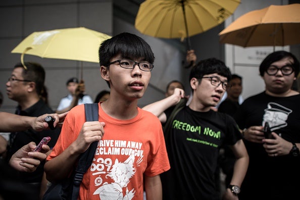 Wong (centre L) and Nathan Law (centre R) stand outside the Wanchai police station in Hong Kong today after reporting to police for investigation into their participation in the 2014 pro-democracy Occupy movement
