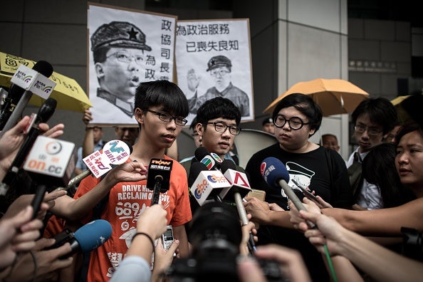 Wong (L) and Nathan Law (C) talk to the media outside the Wanchai police station in Hong Kong today (via PHILIPPE LOPEZ/AFP/Getty Images)