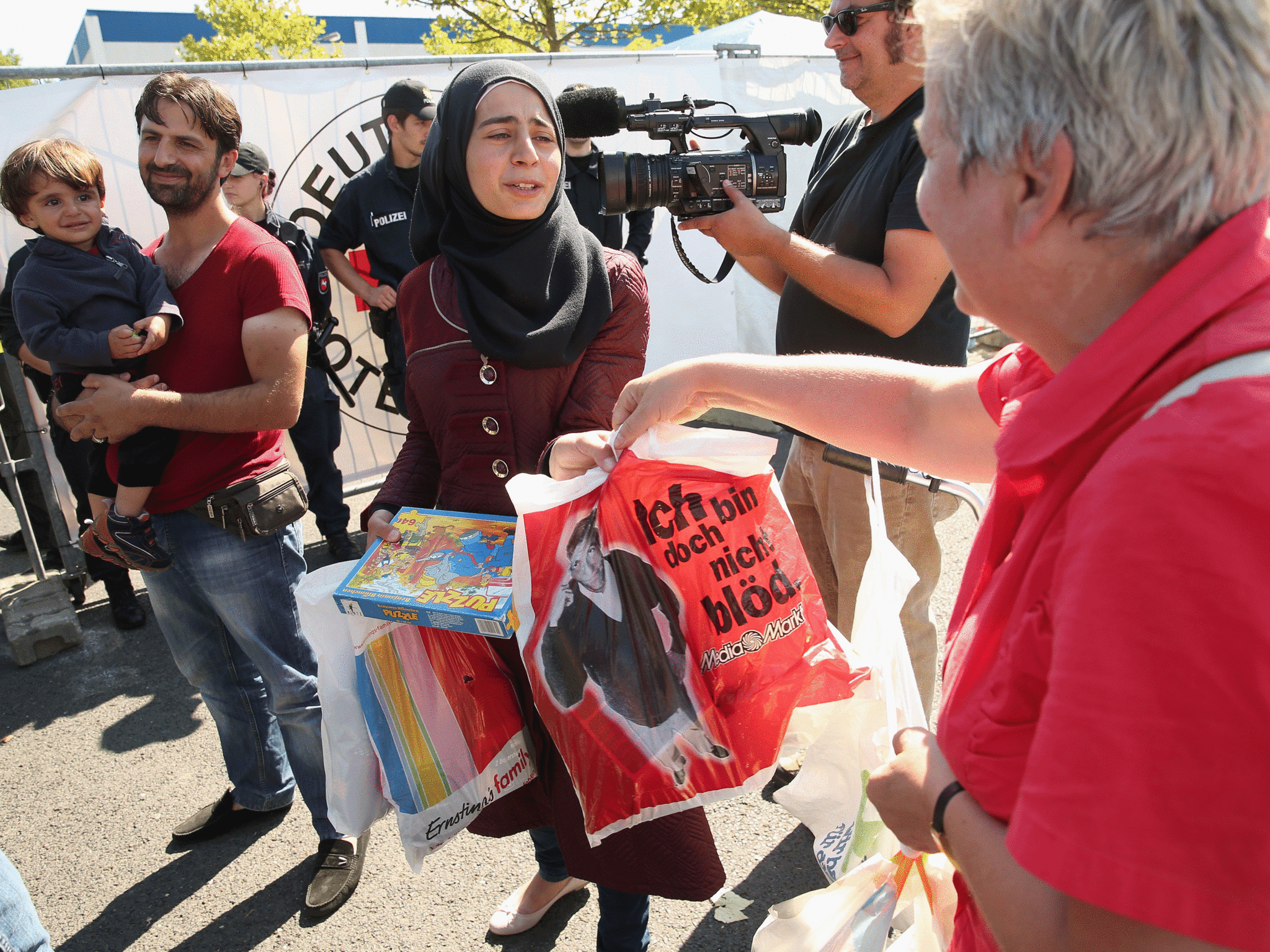 A local woman offers gifts to a Muslim woman from Damascus, Syria, outside a migrants' shelter in Heidenau, Germany