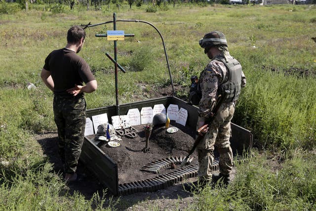 Ukrainian soldiers stand by a memorial for colleagues who died in fighting with pro-Russian rebels in the Donetsk area 