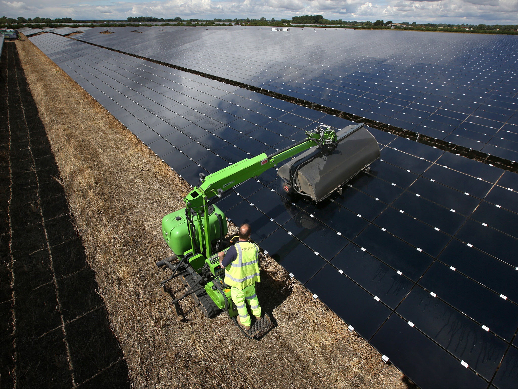 A workman uses a machine to clean panels at Landmead solar farm on July 29, 2015 near Abingdon, England