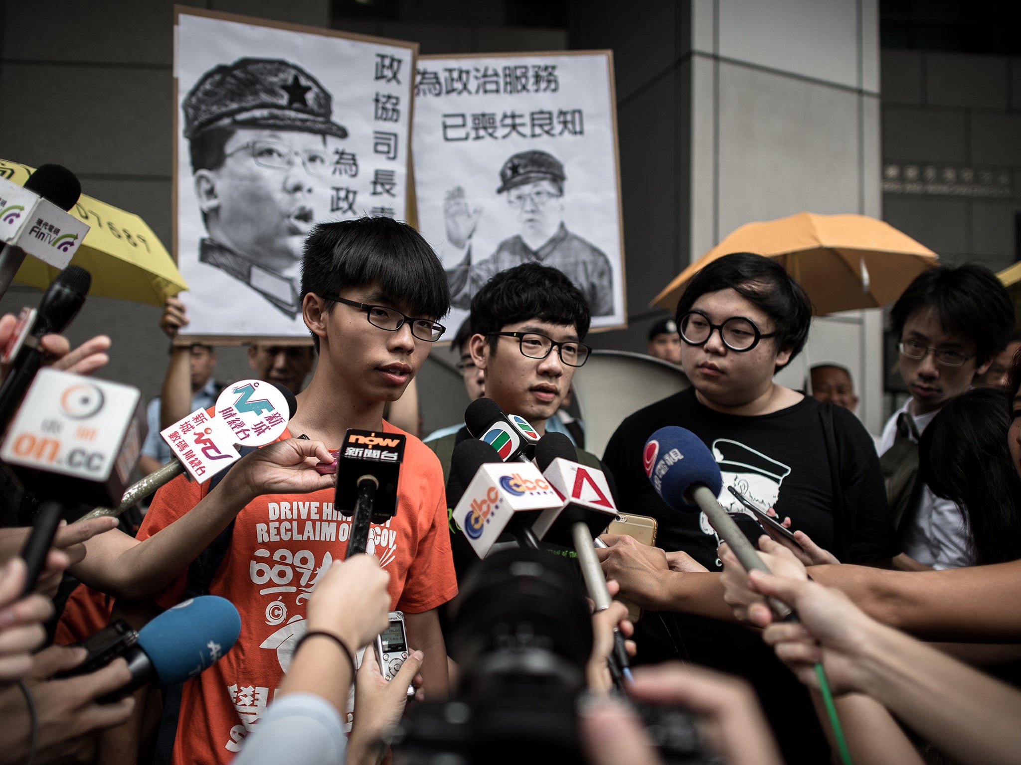 Student protesters Joshua Wong (L) and Nathan Law (C) talk to the media outside the Wanchai police station in Hong Kong on August 27, 2015