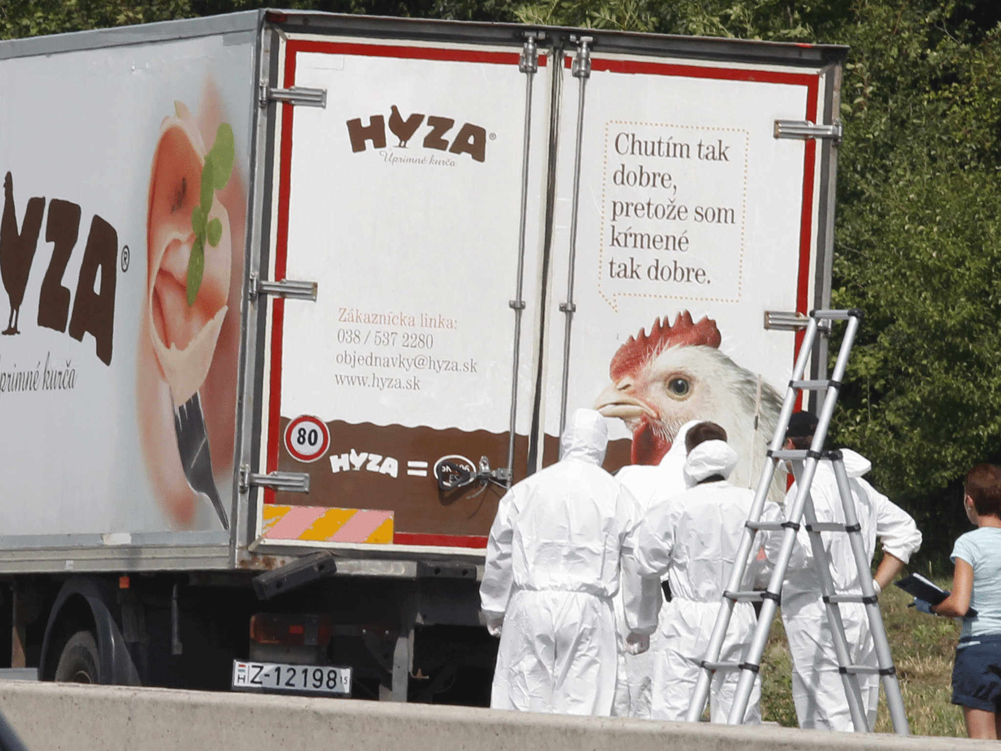 Forensic officers stand in front of the truck in which the migrants were found dead