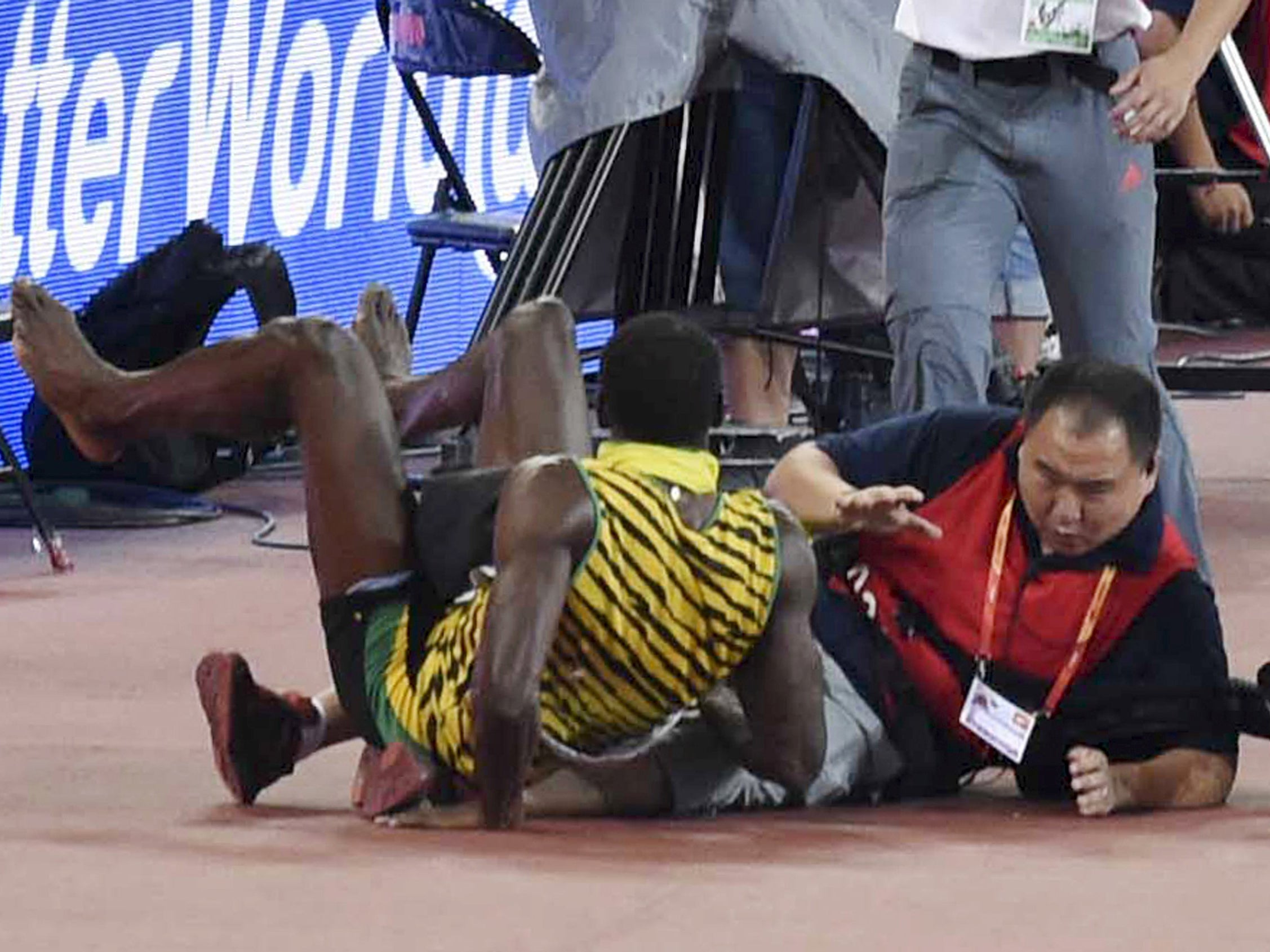 Usain Bolt of Jamaica (L) falls after being knocked over by a cameraman (R) on a Segway after winning the men's 200 metres final
