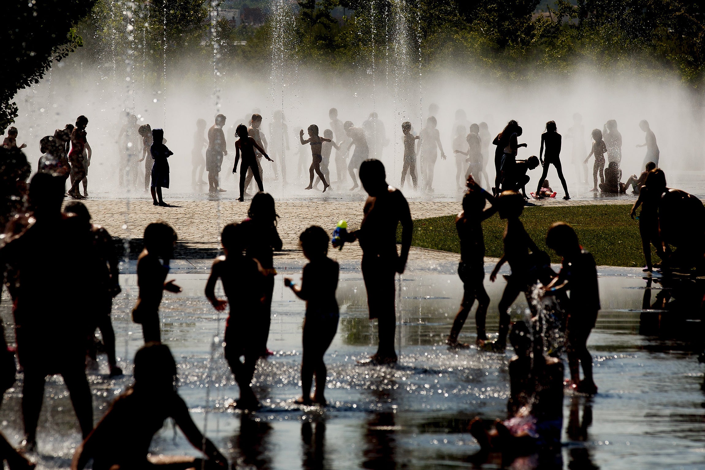 Children cool off as they play under a fountain next to the Manzanares river on July 21, 2015 in Madrid, Spain