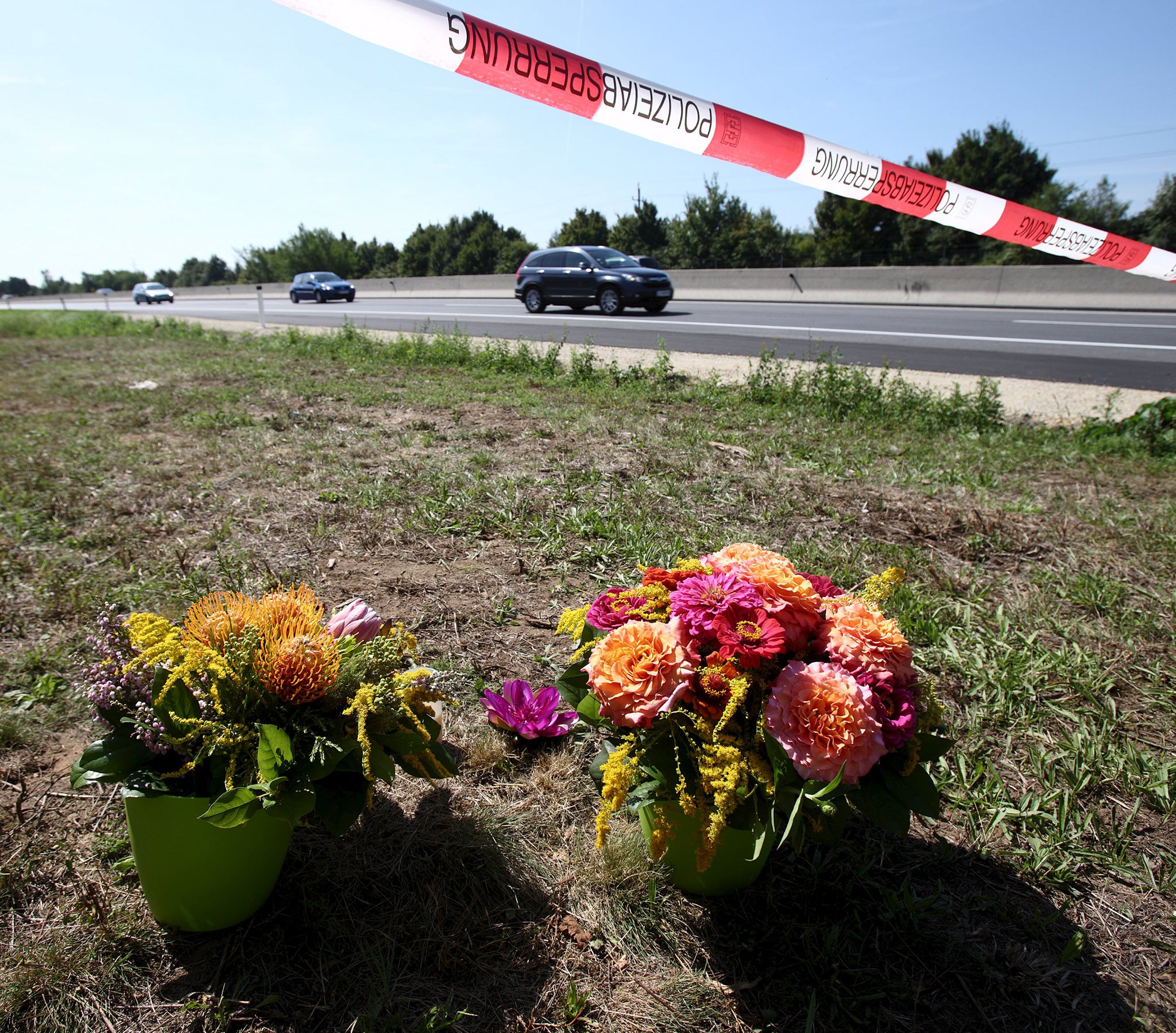 Flowers and candles are placed at the site where a refrigerated truck with decomposing bodies was found by an Austrian motorway