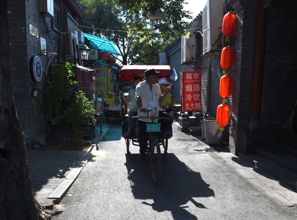 A pedicab rider takes tourists on a guided tour through the back streets of Beijing. Despite the market turmoil in China this week, experts are telling UK investors to remain calm