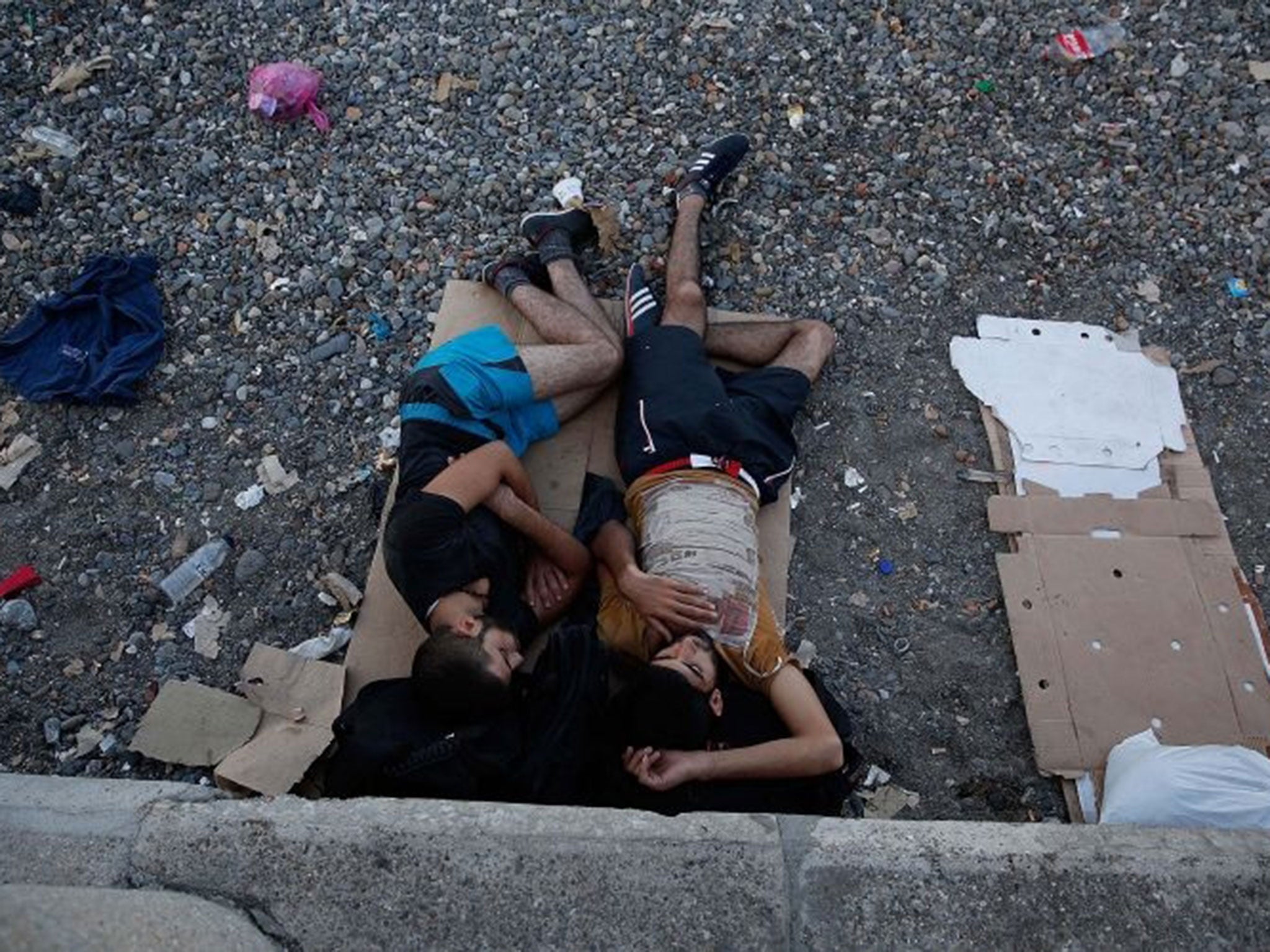Two Syrian migrants who recently arrived in Greece sleep on a public beach August 28, 2015 in Kos, Greece. Migrants from the Middle East and North Africa continue to flood into Europe at a rate that marks the largest migration since World War II.