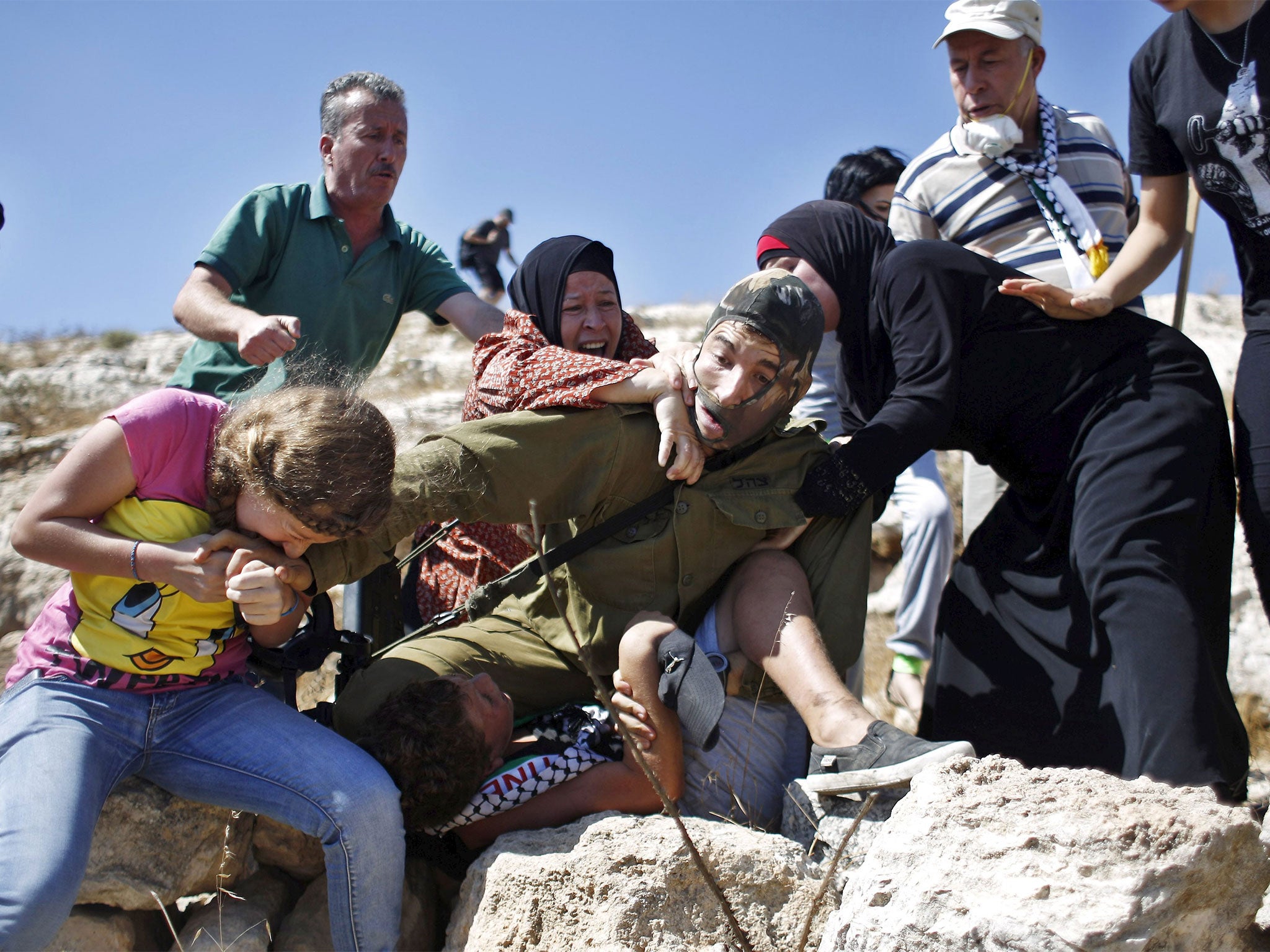 The young girl can be seen biting the Israeli soldier's hand