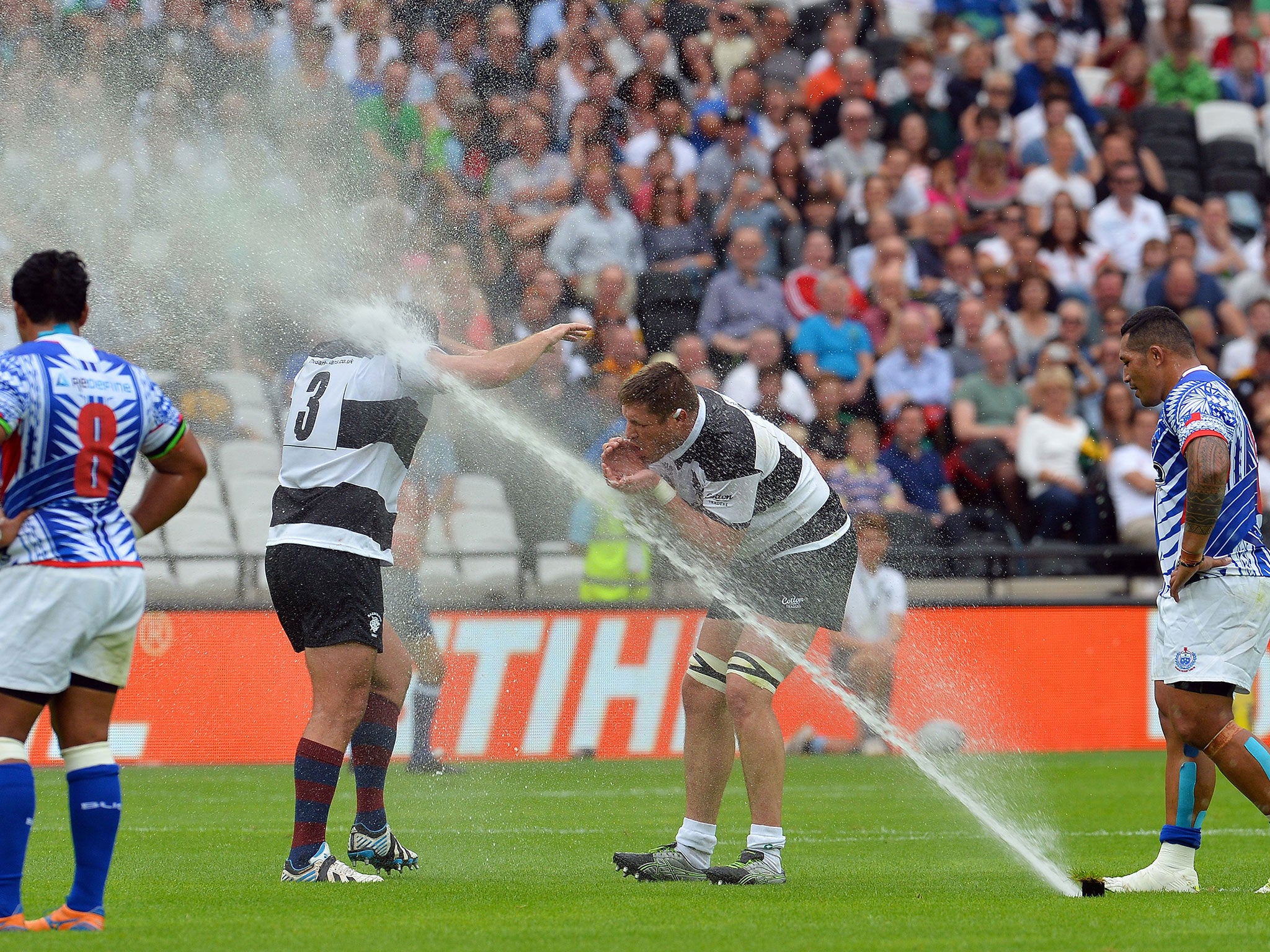 The sprinklers come on during the Barbarians vs Samoa at the Olympic Stadium