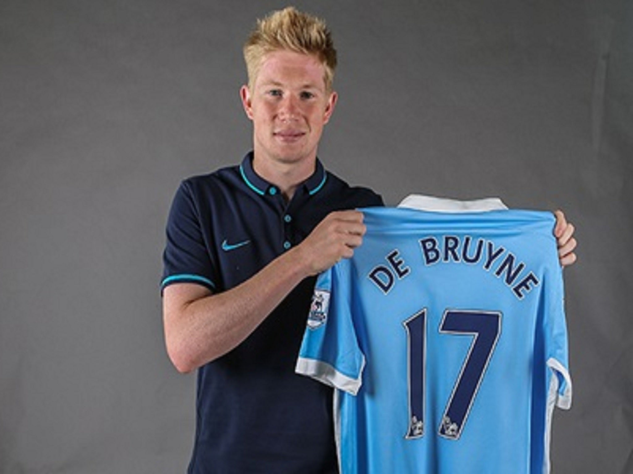 Kevin de Bruyne holds his new Manchester City shirt after completing his move from Wolfsburg