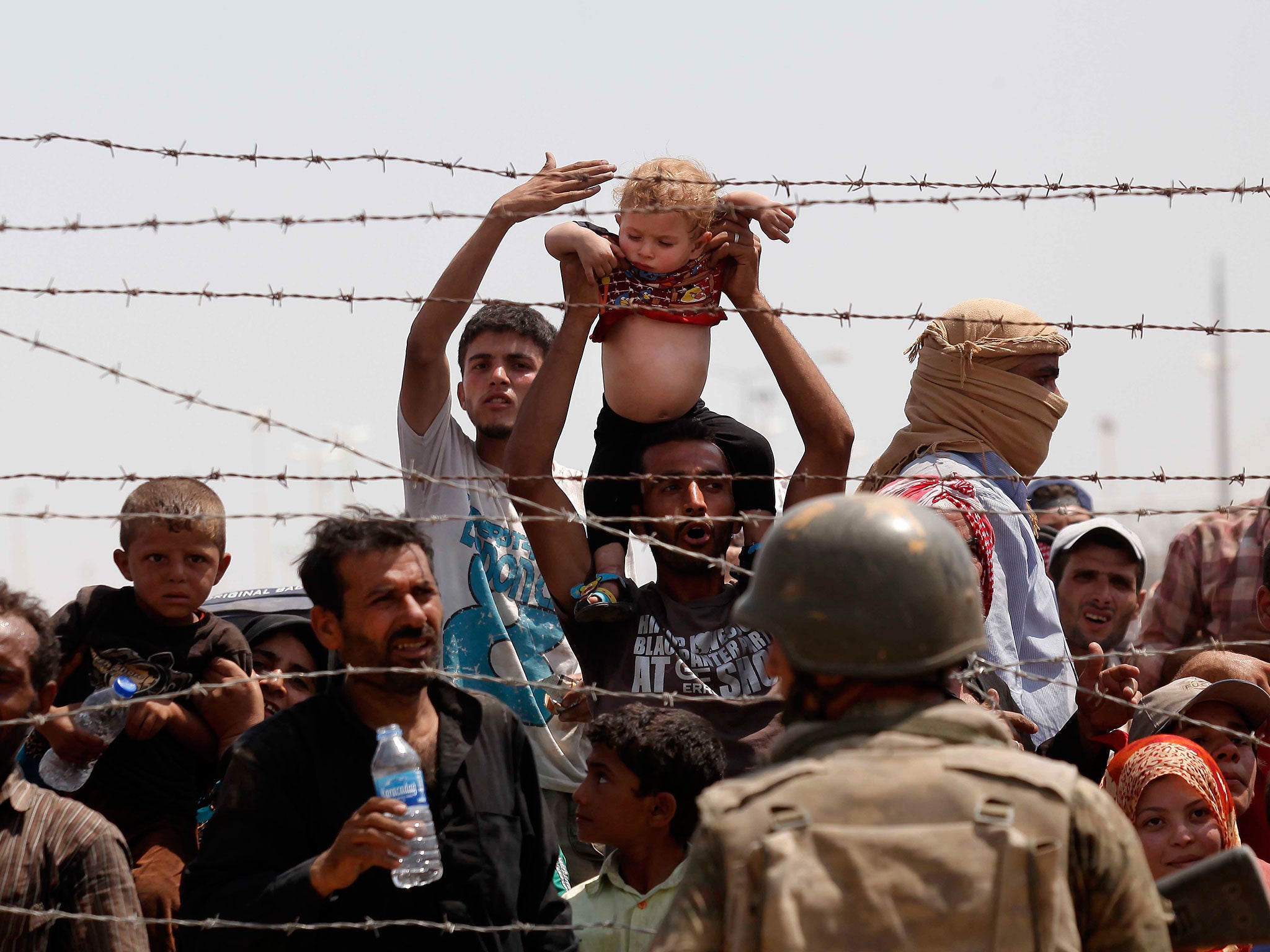 Syrian refugees passing on the Syrian side of the border crossing Akcakale, in Sanliurfa province, southeastern Turkey