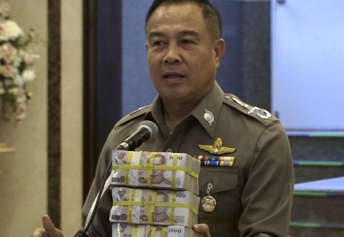 Police chief Somyot Poompanmoung holds a cash reward at a press conference