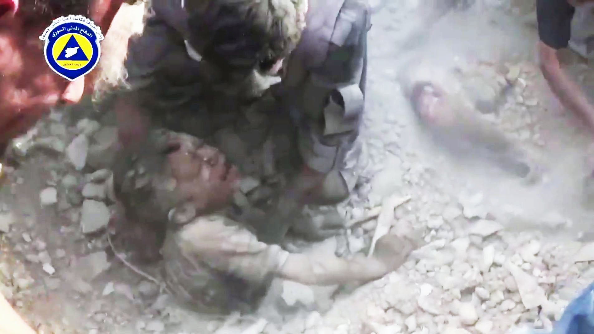 A child is pulled from rubble after an air strike in Saqba, Syria