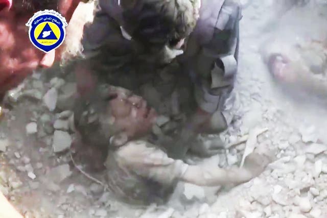 A child is pulled from rubble after an air strike in Saqba, Syria