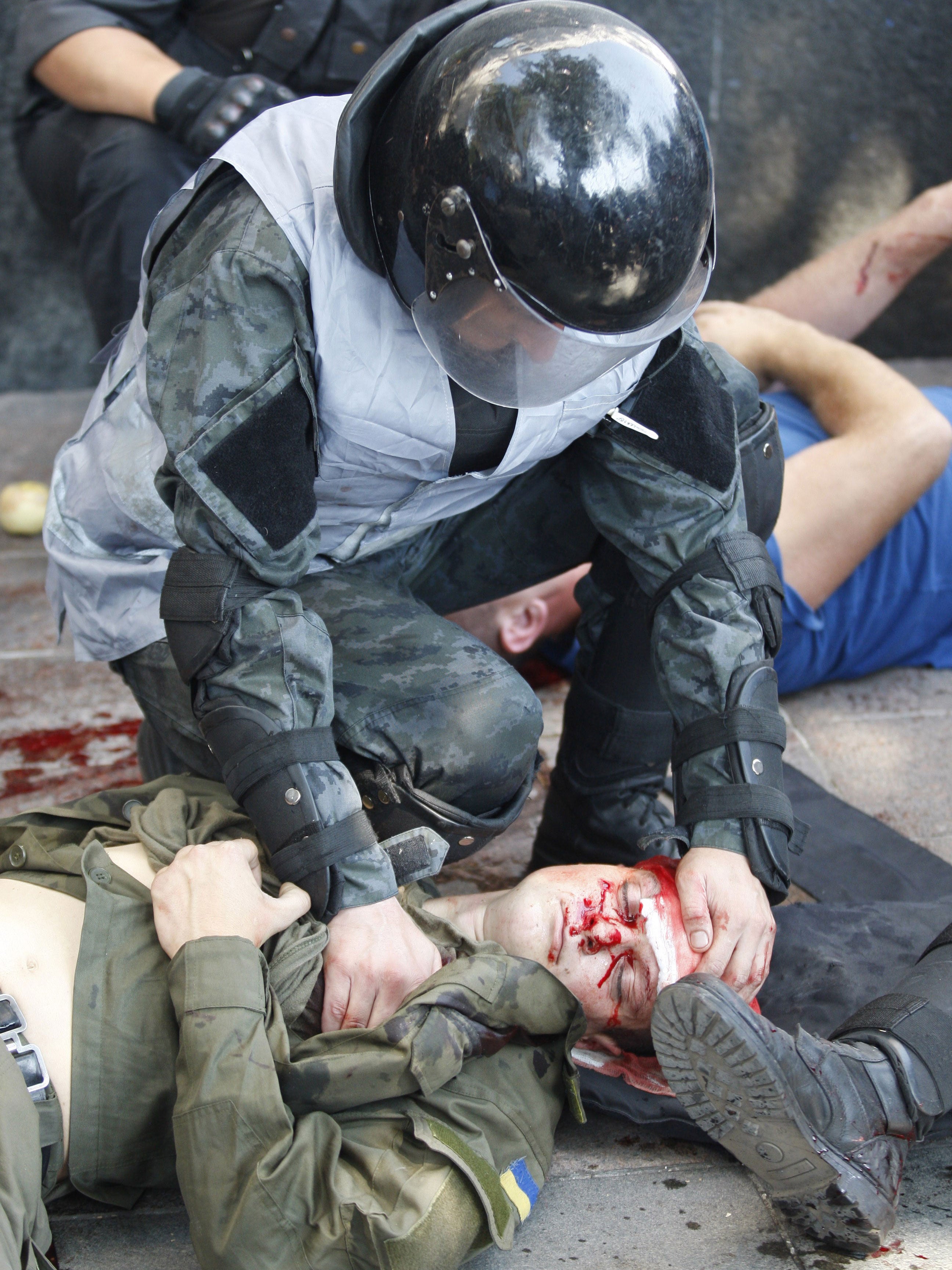 A policeman helps a wounded colleague in Kiev
