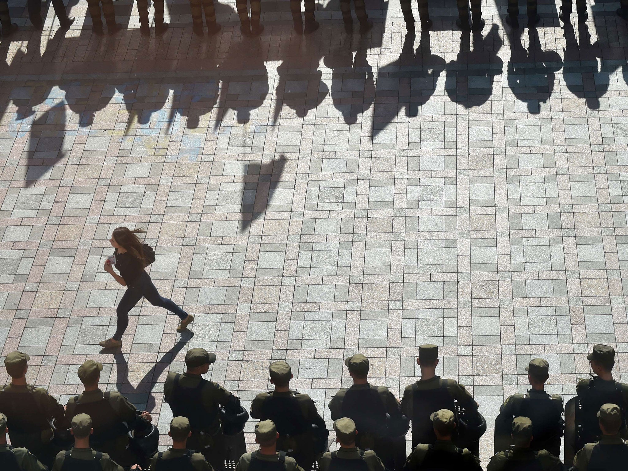 A girl walks by policemen standing guard during a protest by activists of radical Ukrainian parties, including the Ukrainian nationalist party Svoboda (Freedom), in Kiev