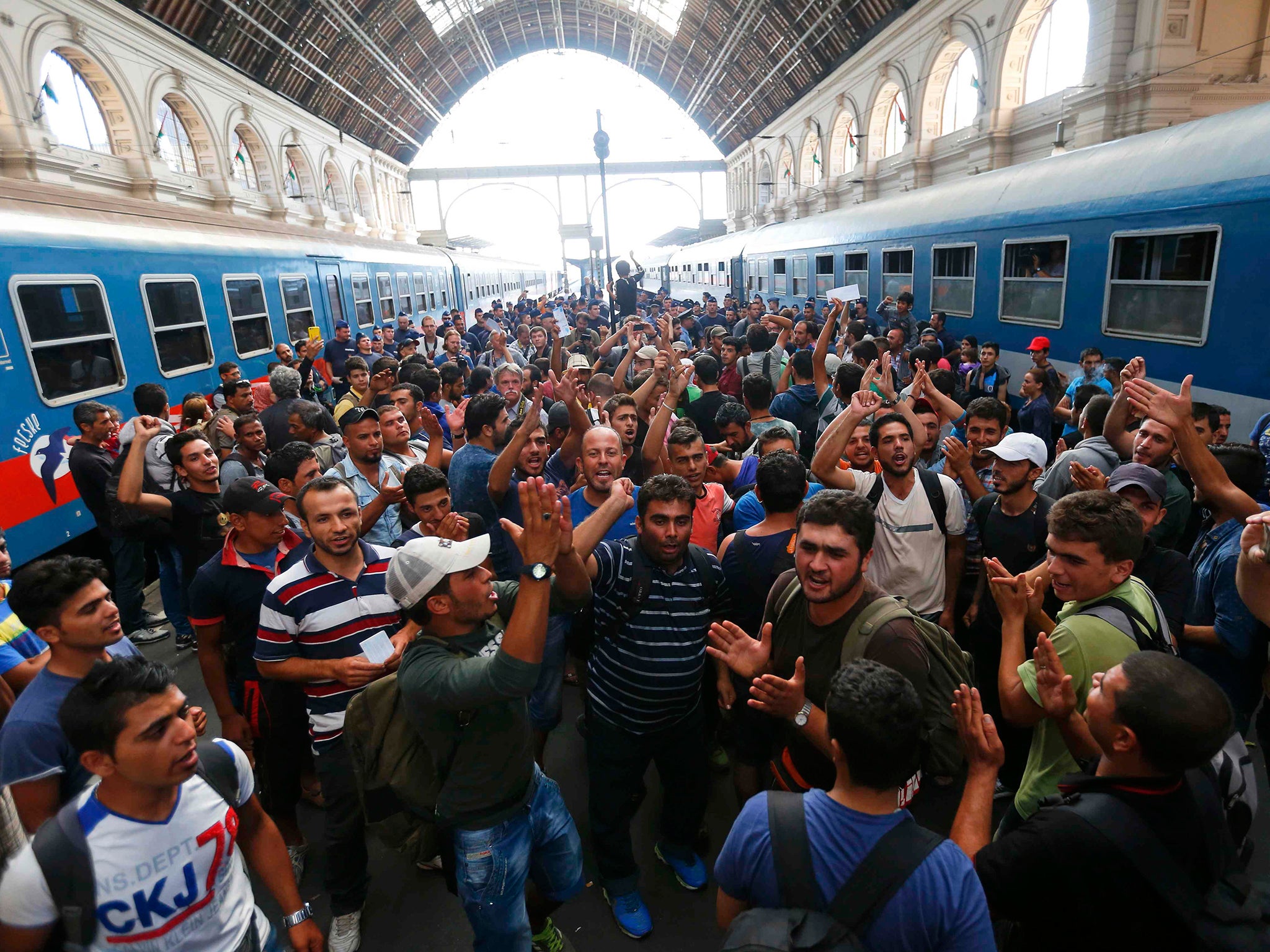 Migrants gesture as they stand in the main Eastern Railway station in Budapest