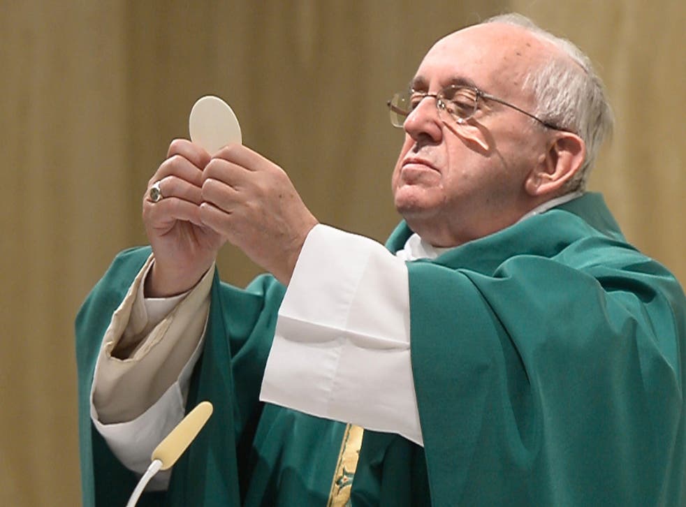 This handout picture released by the Vatican press office (Osservatore Romano) shows Pope Francis holding up sacramental bread as he celebrates mass in Santa Marta at the Vatican on September 1, 2015