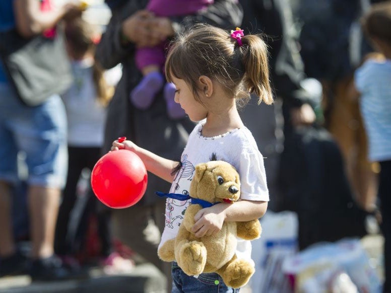 A girl holds a balloon and a teddy bear in a holding area at Munich Hauptbahnhof main railway station on 1 September