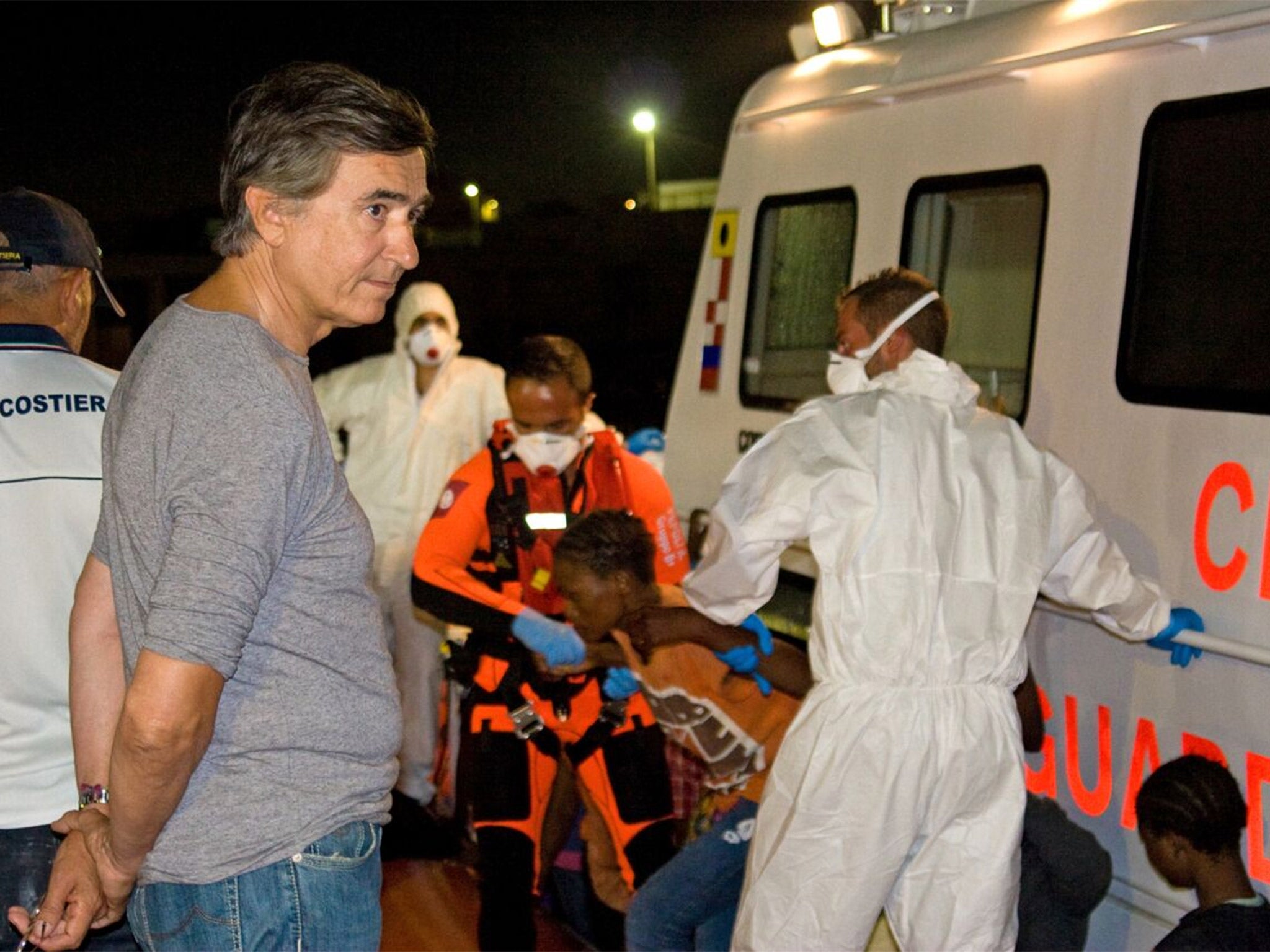 Philippe Douste-Blazy looks on as migrants receive medical attention