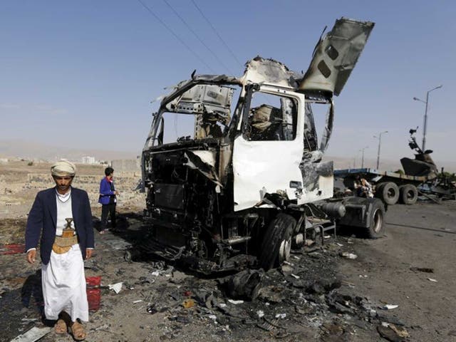 A man stands by a destroyed truck in Amran, the region where two aid workers were killed