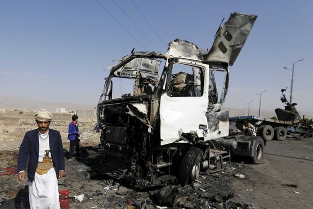 A man stands by a destroyed truck in Amran, the region where two aid workers were killed