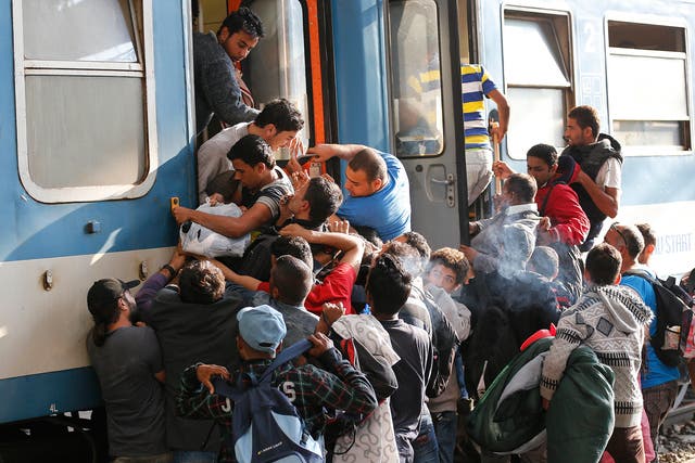 People struggle to board a train at the railway station in Budapest