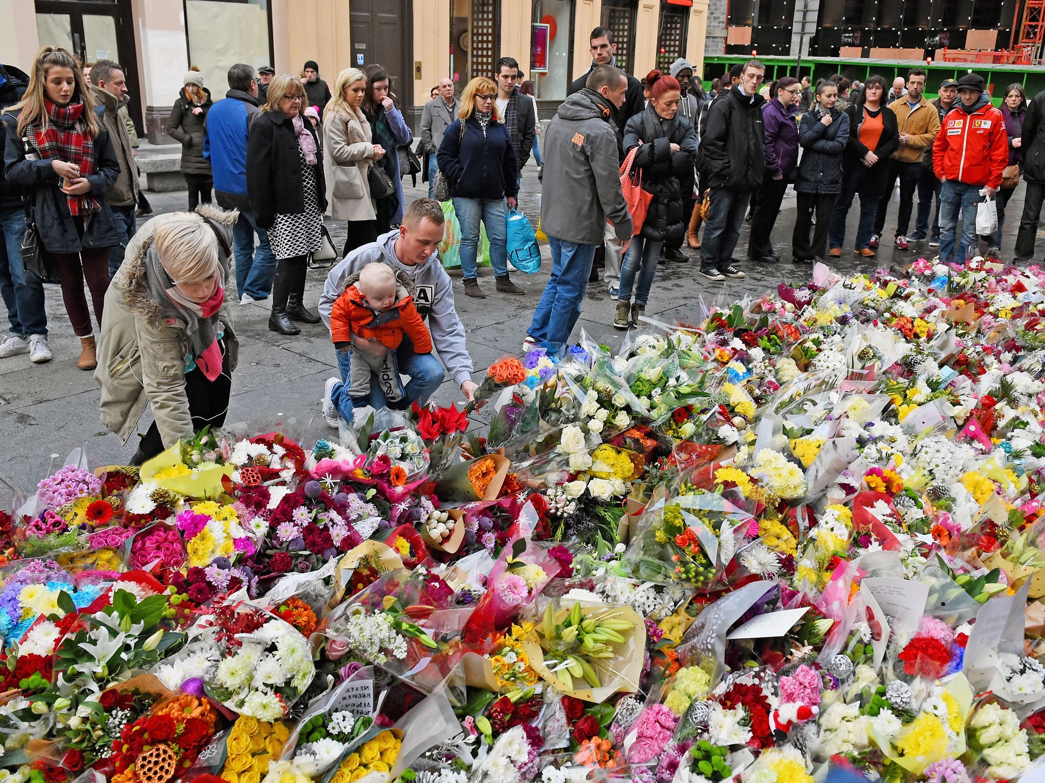 People lay floral tributes near to the scene of the bin lorry crash, a day after the tragedy on 23 December, 2014 in Glasgow