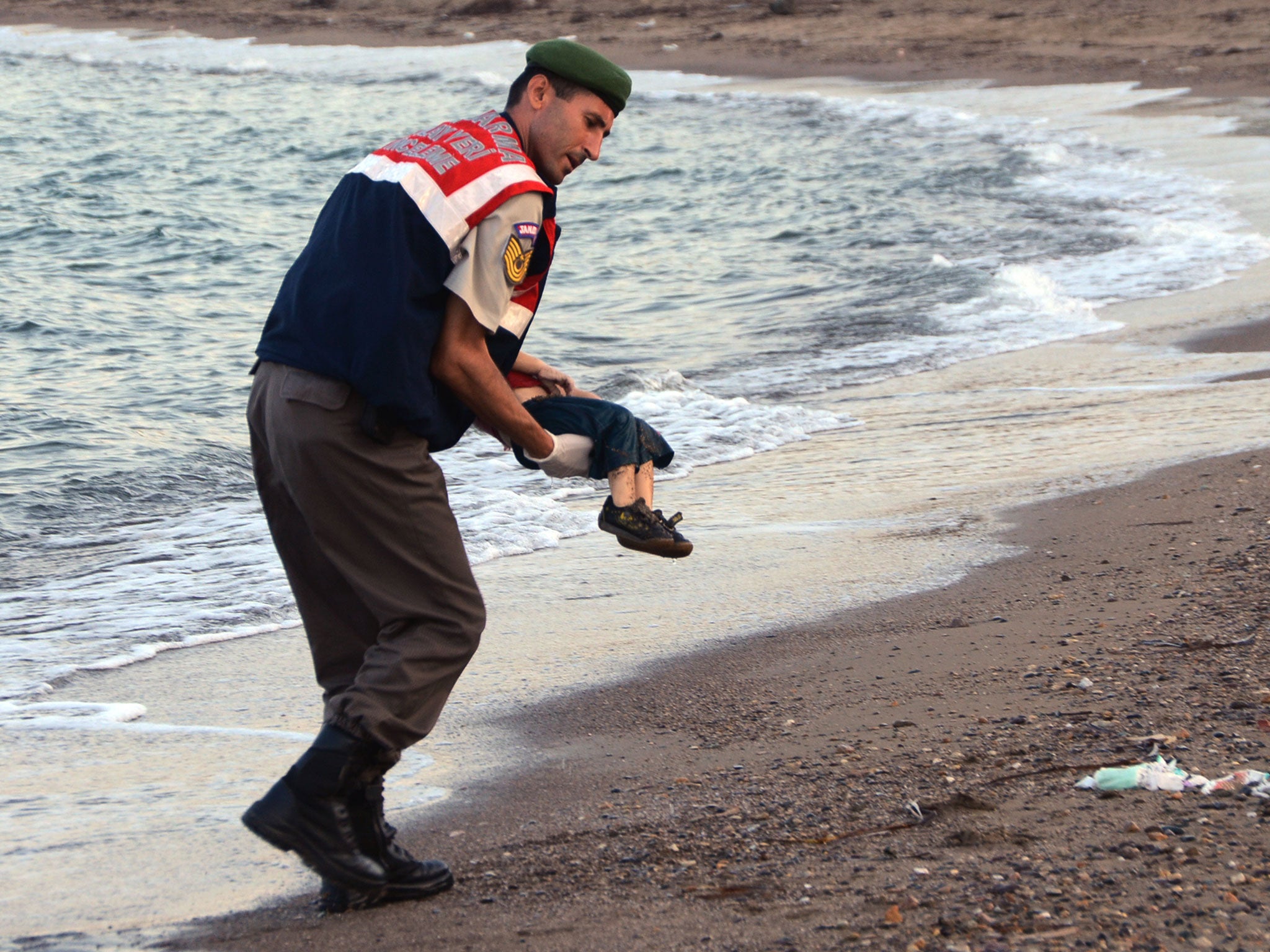 A paramilitary police officer carries the body of Aylan Kurdi